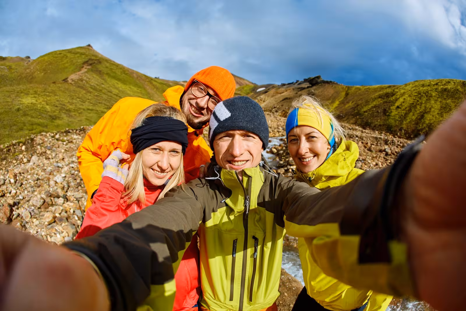 Group of friends smiling while taking a selfie in vibrant outdoor gear during Iceland's self-drive adventure.