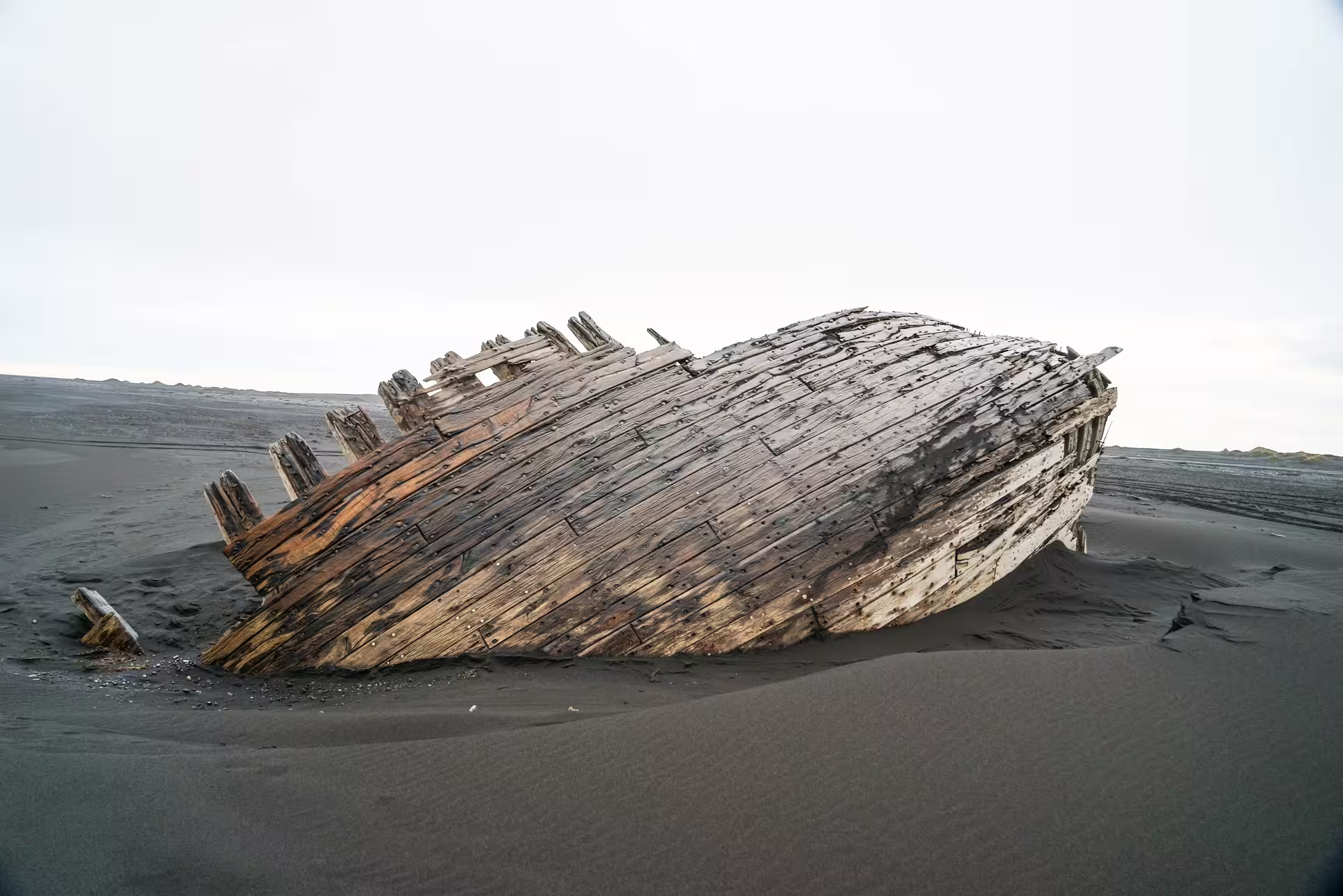 Historic wooden shipwreck resting on Iceland black sand beach near Thorsmork Valley guided day tour from Reykjavik
