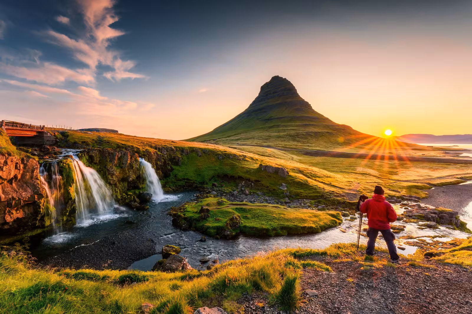 Traveler admires sunrise over Kirkjufell mountain and waterfall on Iceland's Snæfellsnes Peninsula during a 9-day self-drive tour.