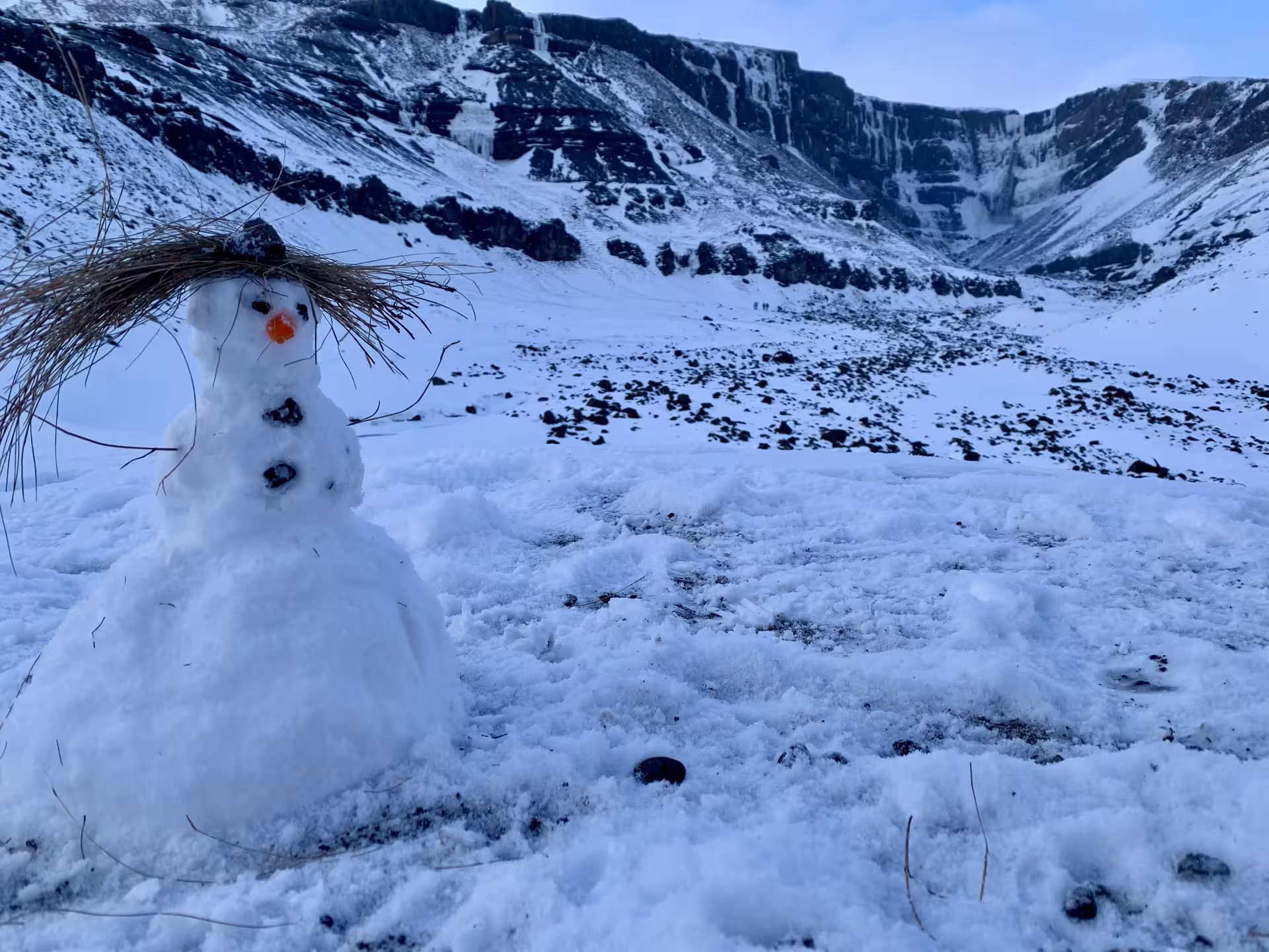 A whimsical snowman with a straw hat in snowy Icelandic wilderness on a women-only New Year's Eve adventure.