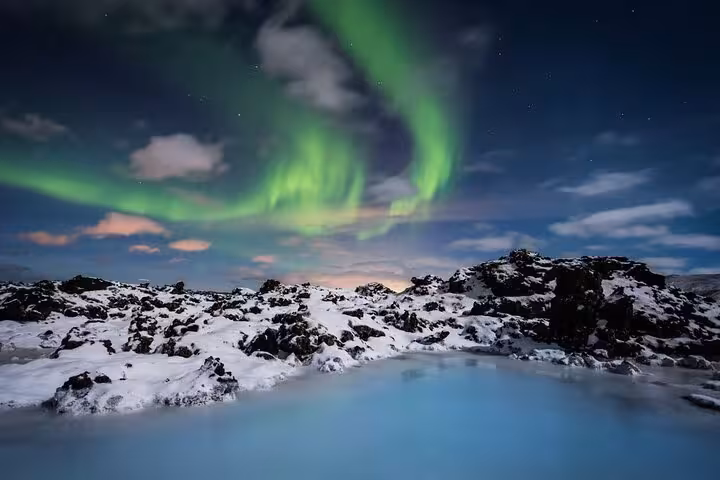 Northern lights aurora borealis over snowy lava fields and blue lagoon waters in Iceland