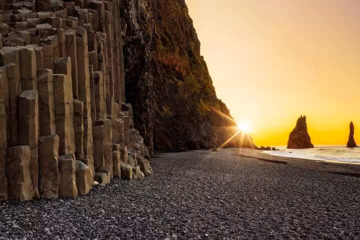 Basalt columns and Reynisdrangar sea stacks at golden sunset on Iceland's black sand beach