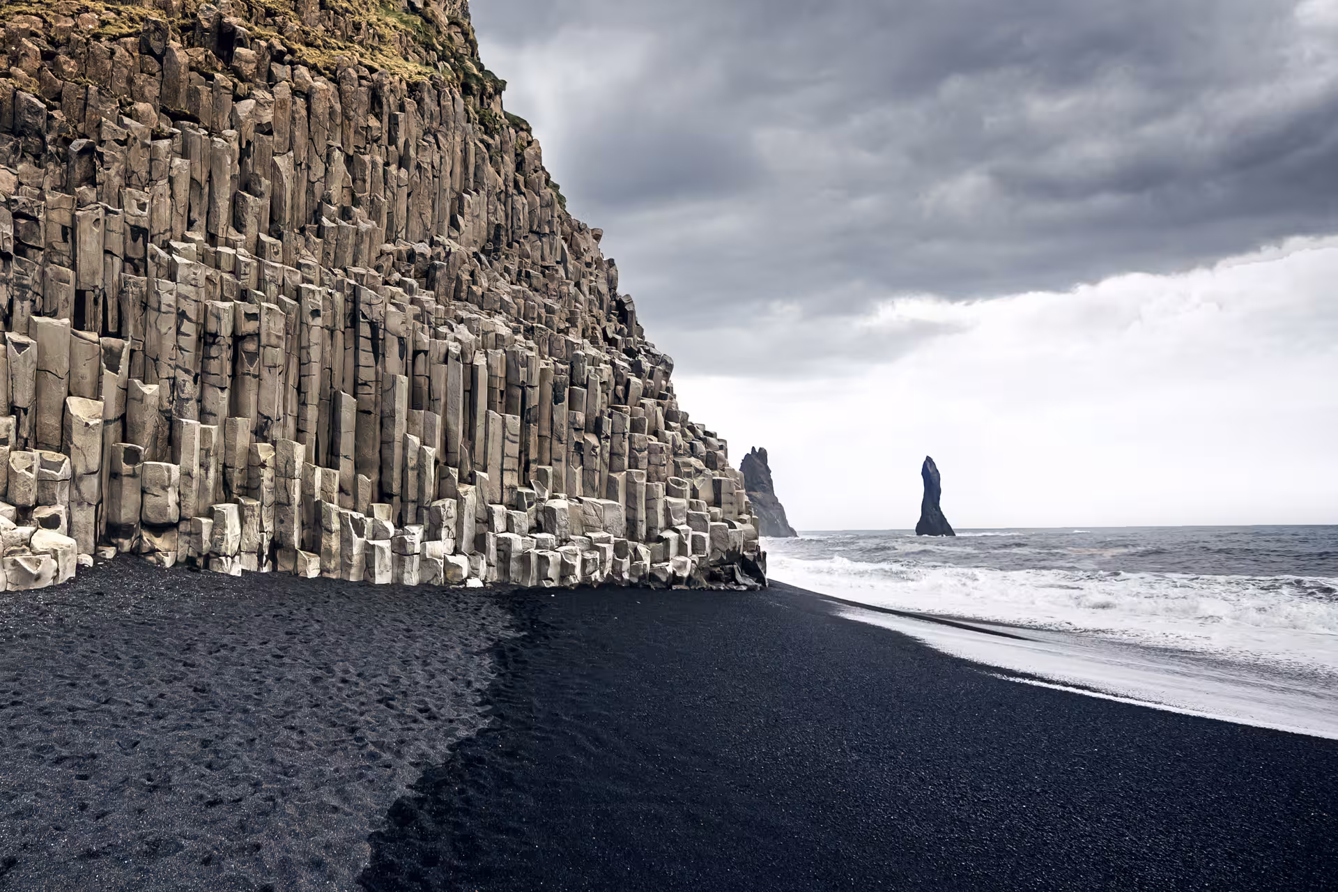 Black sand beach with basalt column cliffs and sea stack on Iceland's dramatic south coast