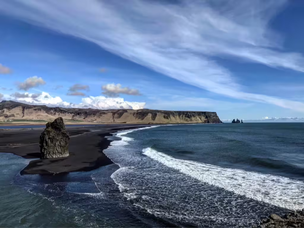 Black sand beach with volcanic rock stack and Reynisdrangar sea stacks along Iceland's South Coast