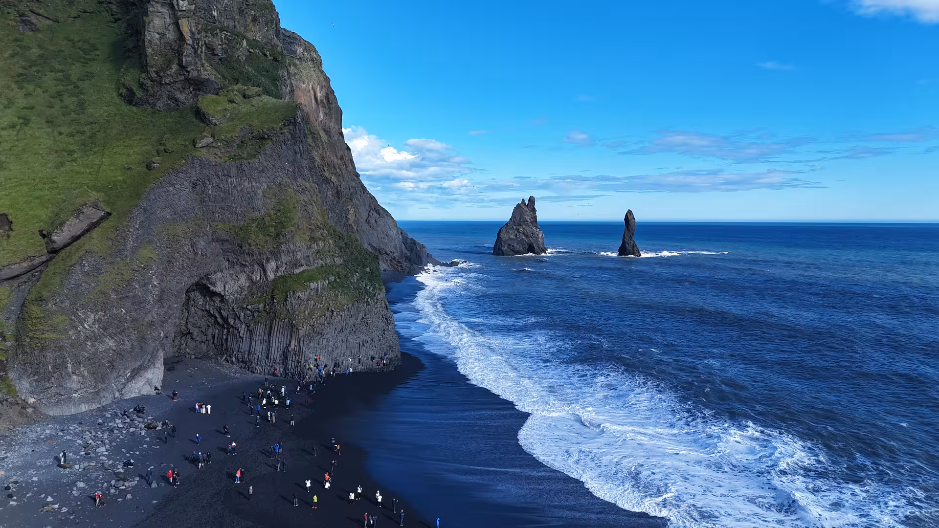 Aerial view of Reynisfjara black sand beach with basalt sea stacks and cliffs on Iceland's South Coast