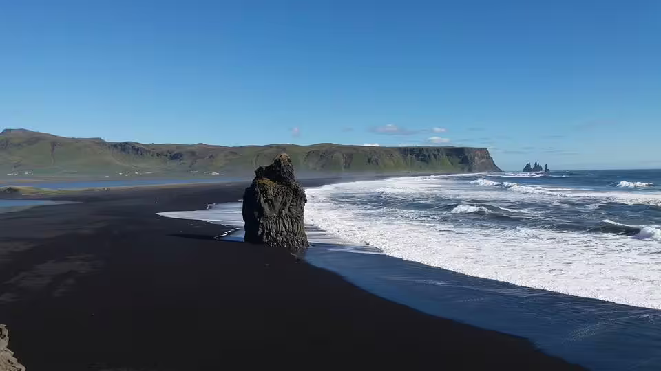 Black sand beach with volcanic rock stack and crashing waves on Iceland's South Coast