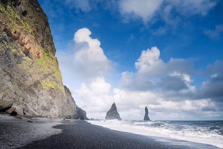 Black sand beach with dramatic basalt sea stacks and waves on Iceland's South Coast
