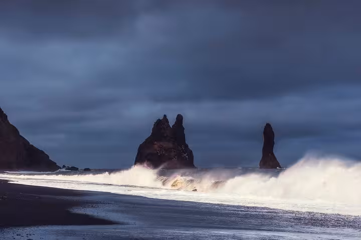Dramatic black sand beach with volcanic sea stacks and crashing waves on Iceland's South Coast