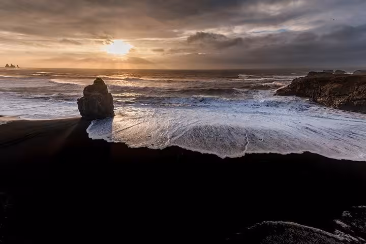 Black sand beach with crashing waves and dramatic sunset on Iceland's South Coast