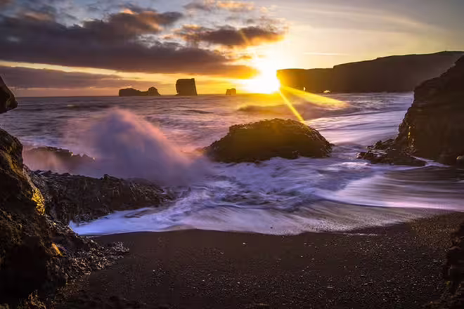 Black sand beach with crashing waves and dramatic sunset at Iceland's South Coast