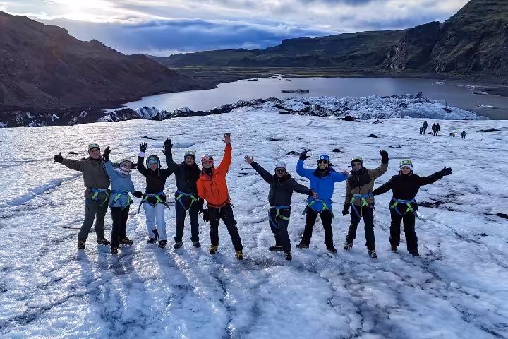 Group of nine hikers with harnesses and helmets posing on Sólheimajökull glacier in Iceland