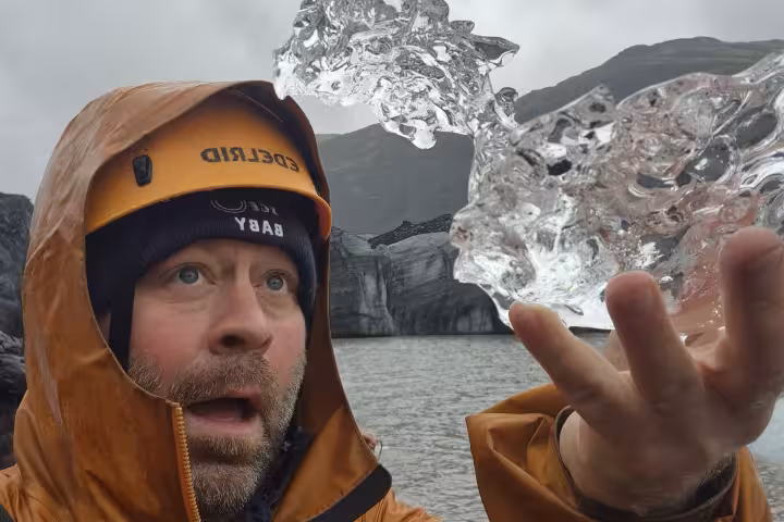 Guide holding glacial ice chunk near Iceland glacier lagoon on south coast tour