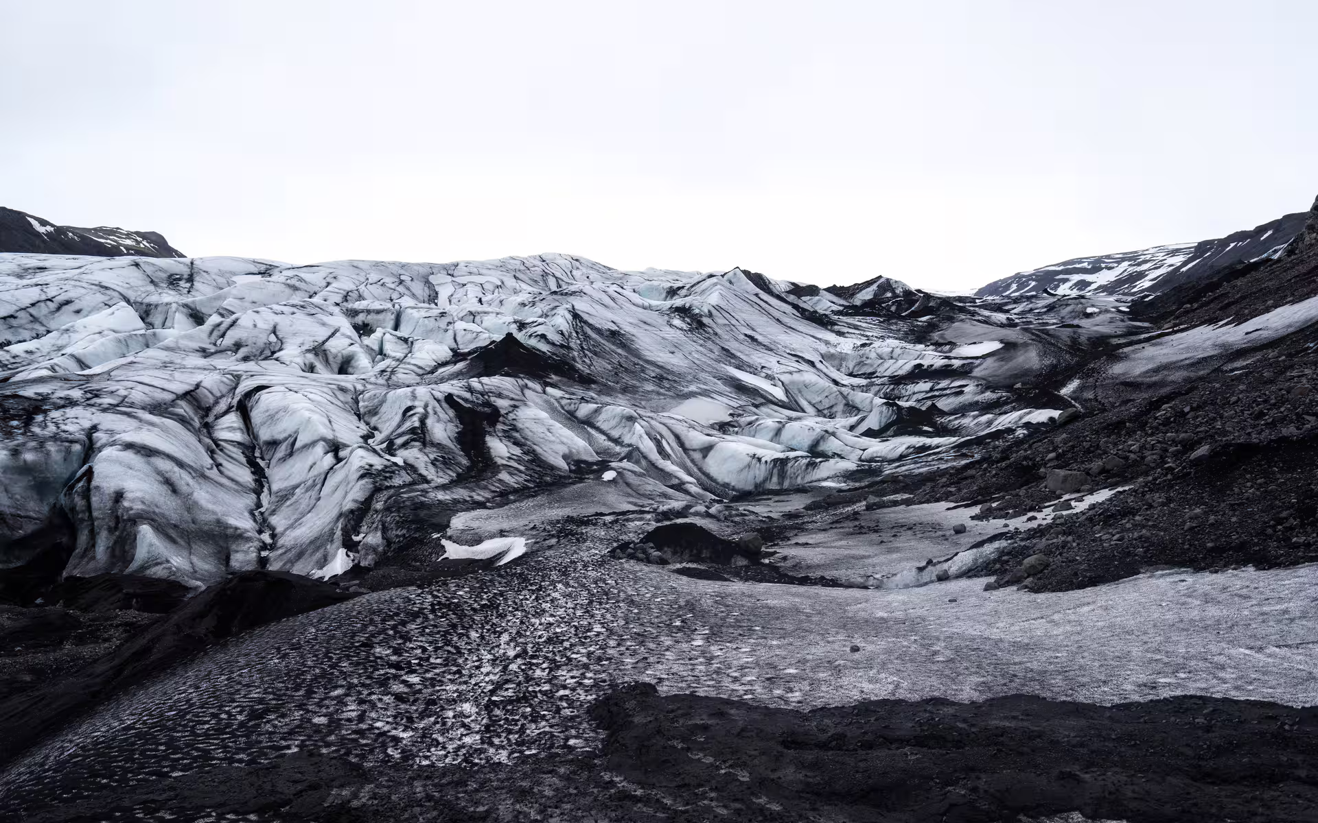 Glacier with dark volcanic ash streaks on Iceland's South Coast under overcast sky