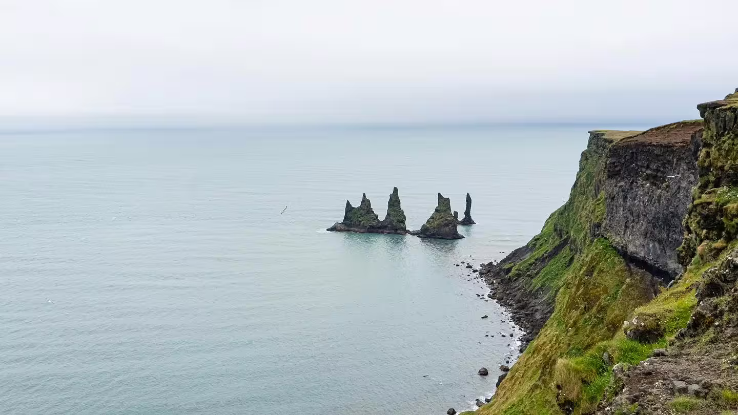 Reynisdrangar basalt sea stacks rising from the ocean along Iceland's dramatic South Coast cliffs