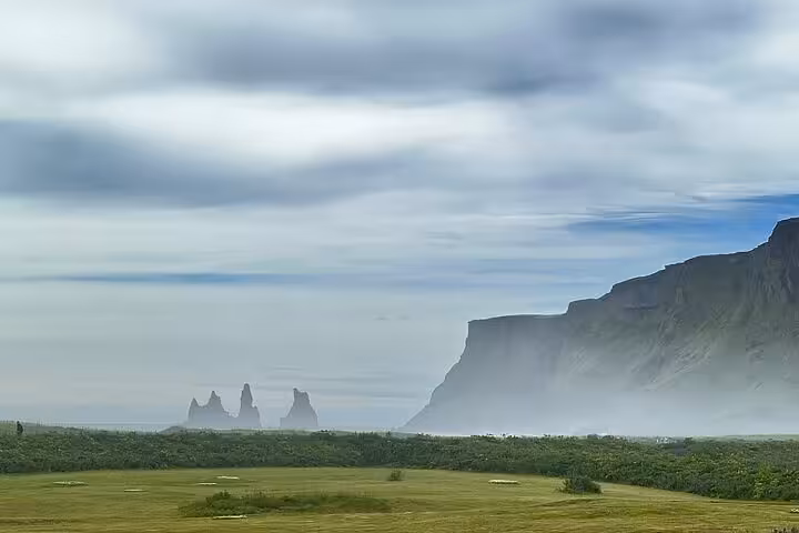 Misty Iceland south coast with Reynisdrangar sea stacks and dramatic black cliffs under cloudy sky