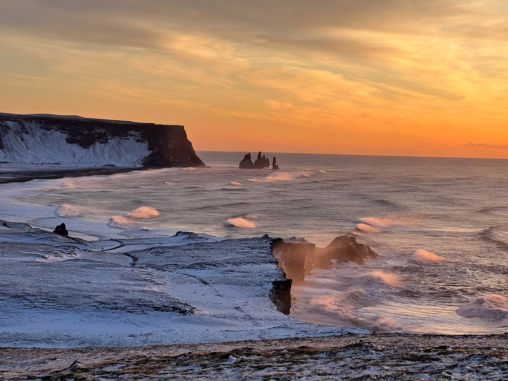 Reynisdrangar sea stacks at sunset with snow-covered black sand beach on Iceland's South Coast in winter