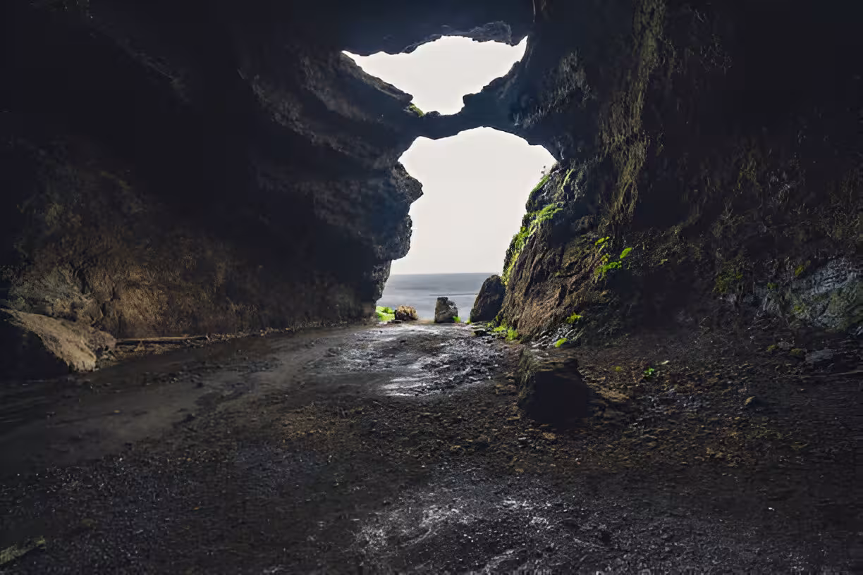View from inside a dark sea cave opening to the ocean on Iceland's south coast