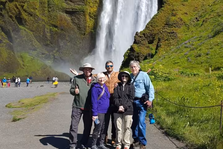 Tour group of five posing in front of Skógafoss waterfall on Iceland South Coast guided day trip