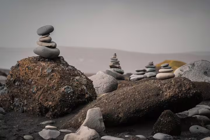 Stacked stone cairns on rocky black sand beach along Iceland's South Coast