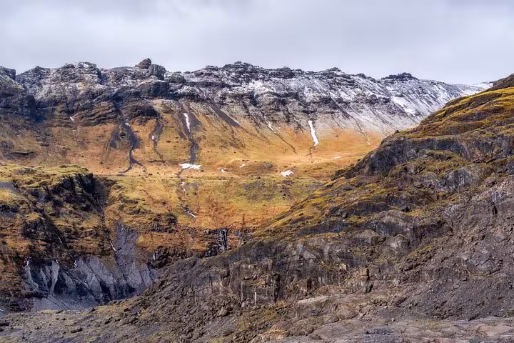 Rugged volcanic mountain valley with snow-dusted peaks and autumn colors on Iceland's south coast