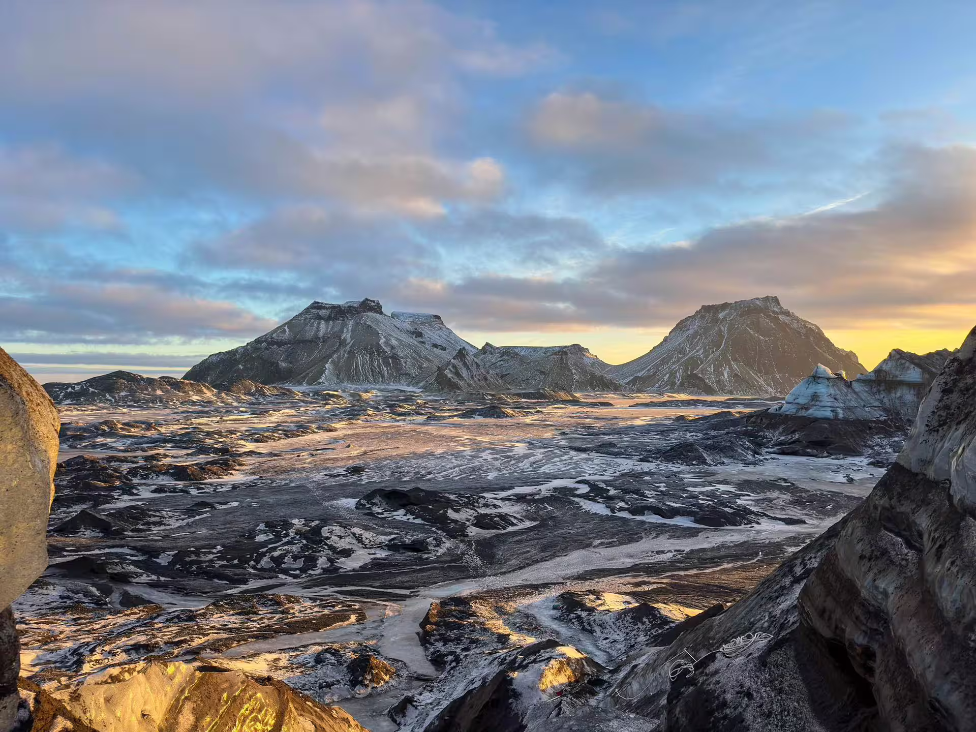 Dramatic volcanic landscape with snow-dusted mountains at golden hour on Iceland South Coast day trip from Reykjavik