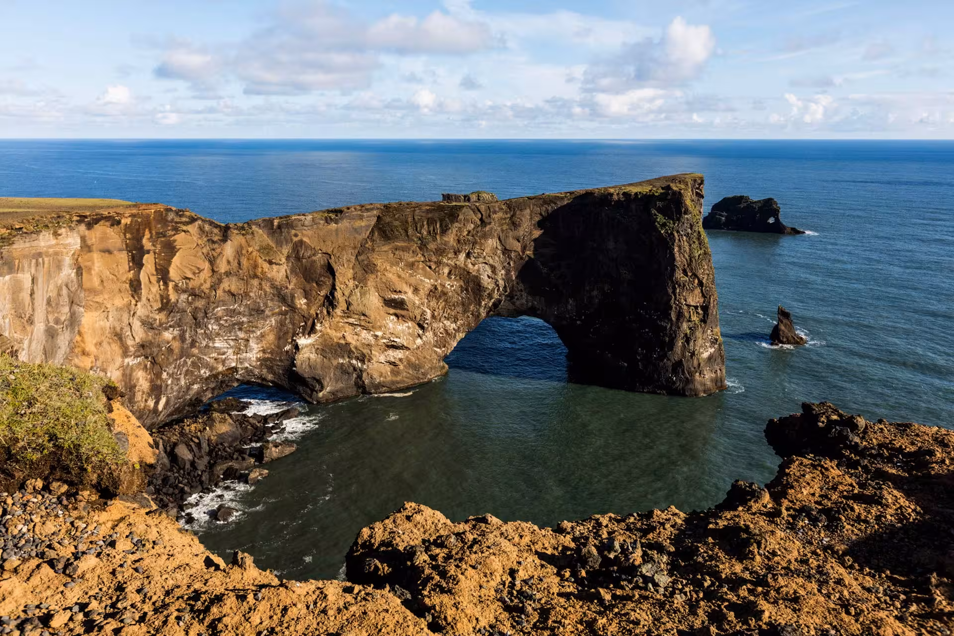 Dramatic volcanic rock arch over the ocean on Iceland's south coast under blue skies