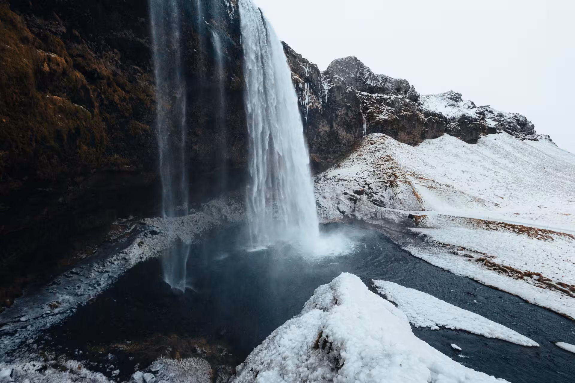 Seljalandsfoss waterfall cascading into snowy pool on Iceland's south coast in winter