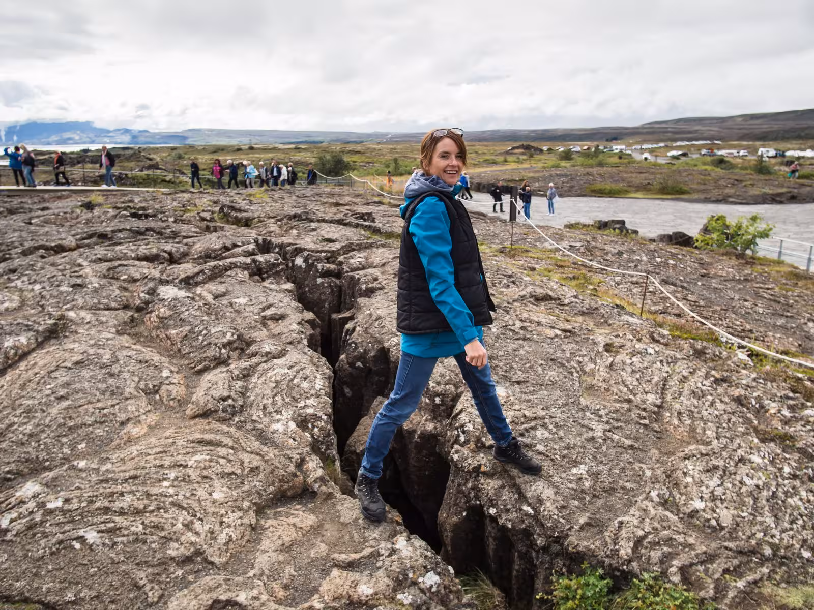 Tourist exploring the dramatic geological rifts at Thingvellir National Park during Iceland stopover tour.