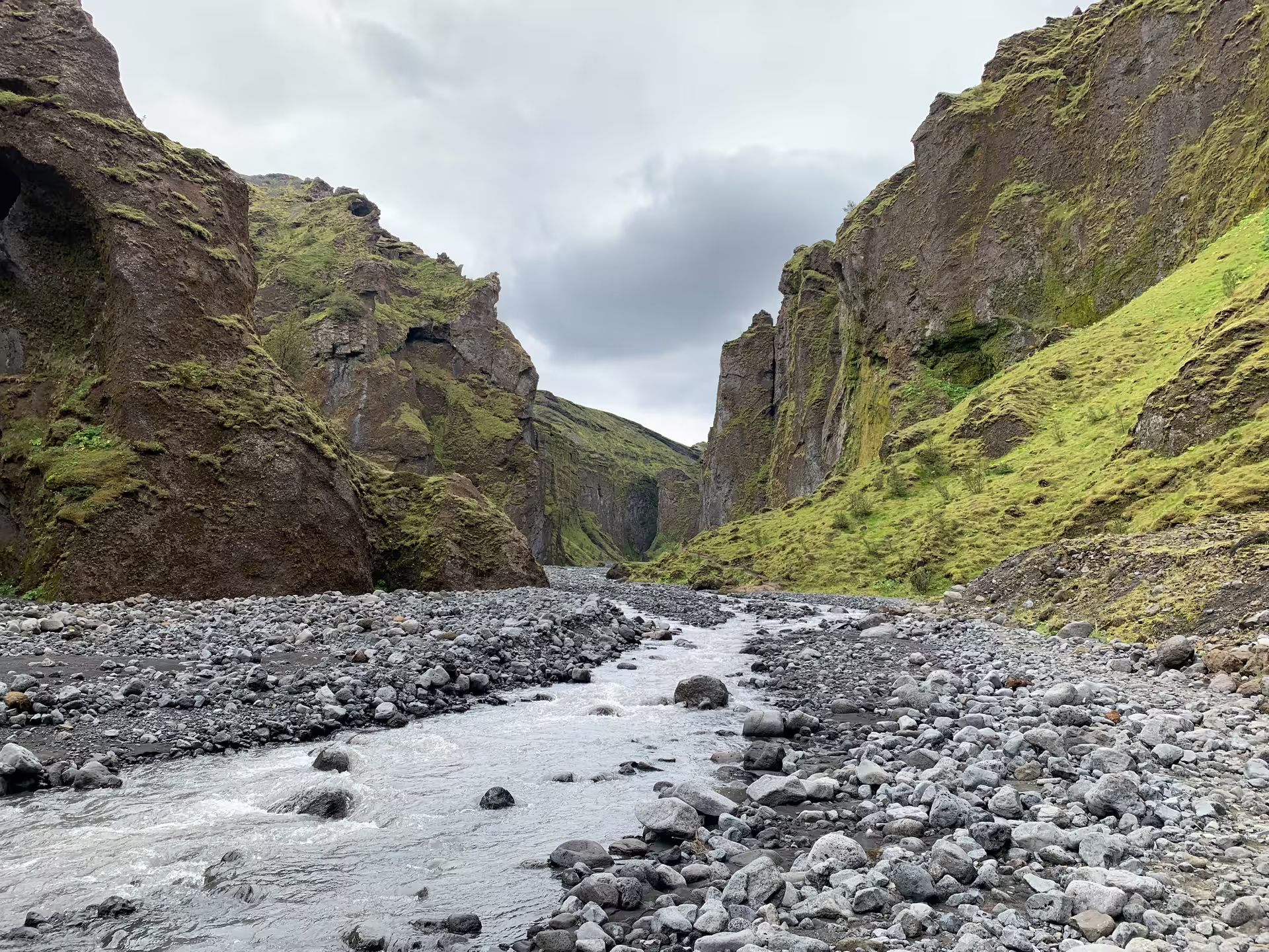 Rocky river flowing through a narrow moss-covered canyon in Iceland on a cloudy day