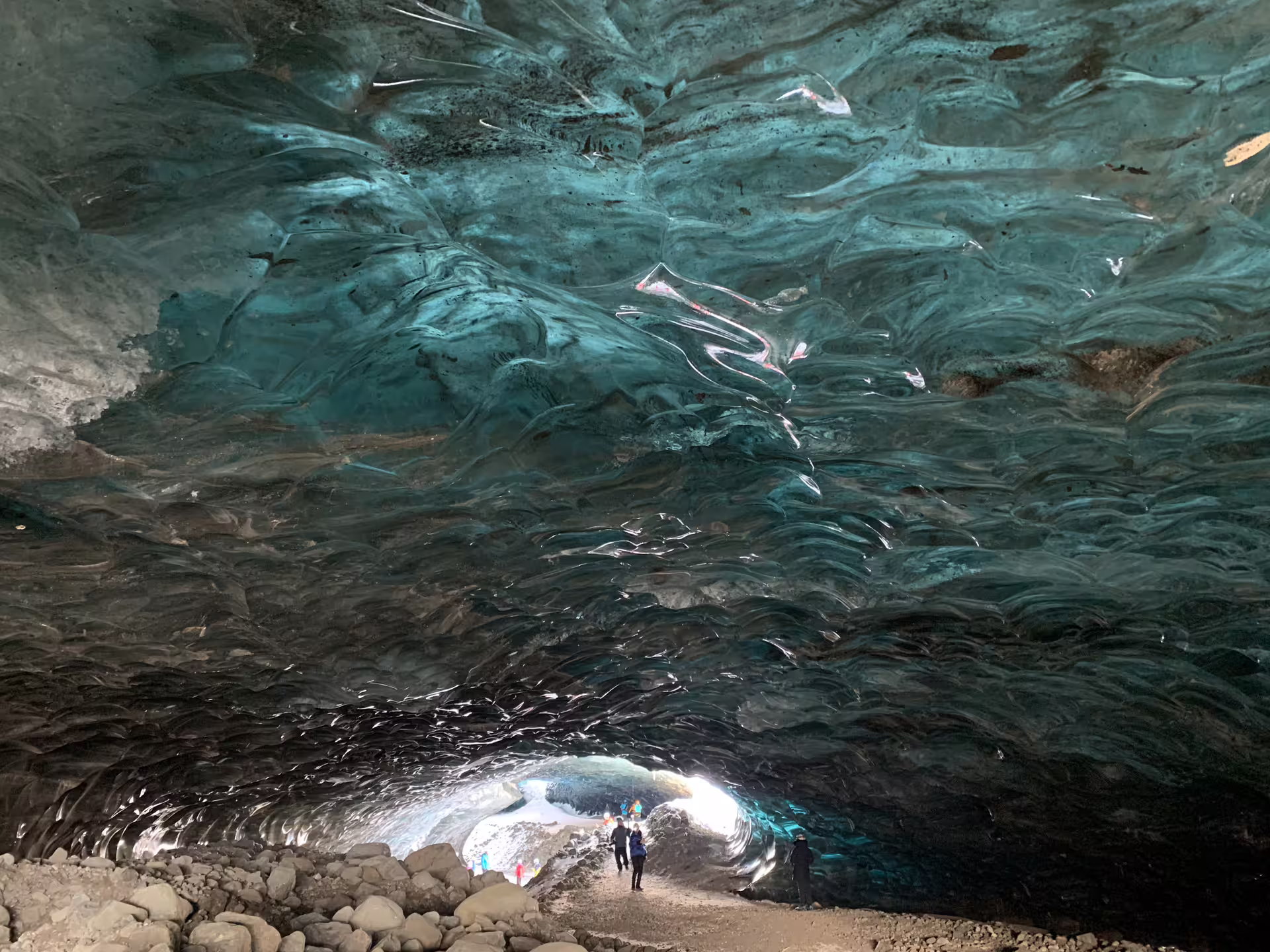 Tourists exploring a vast glacial ice cave with stunning blue ice ceiling in Iceland