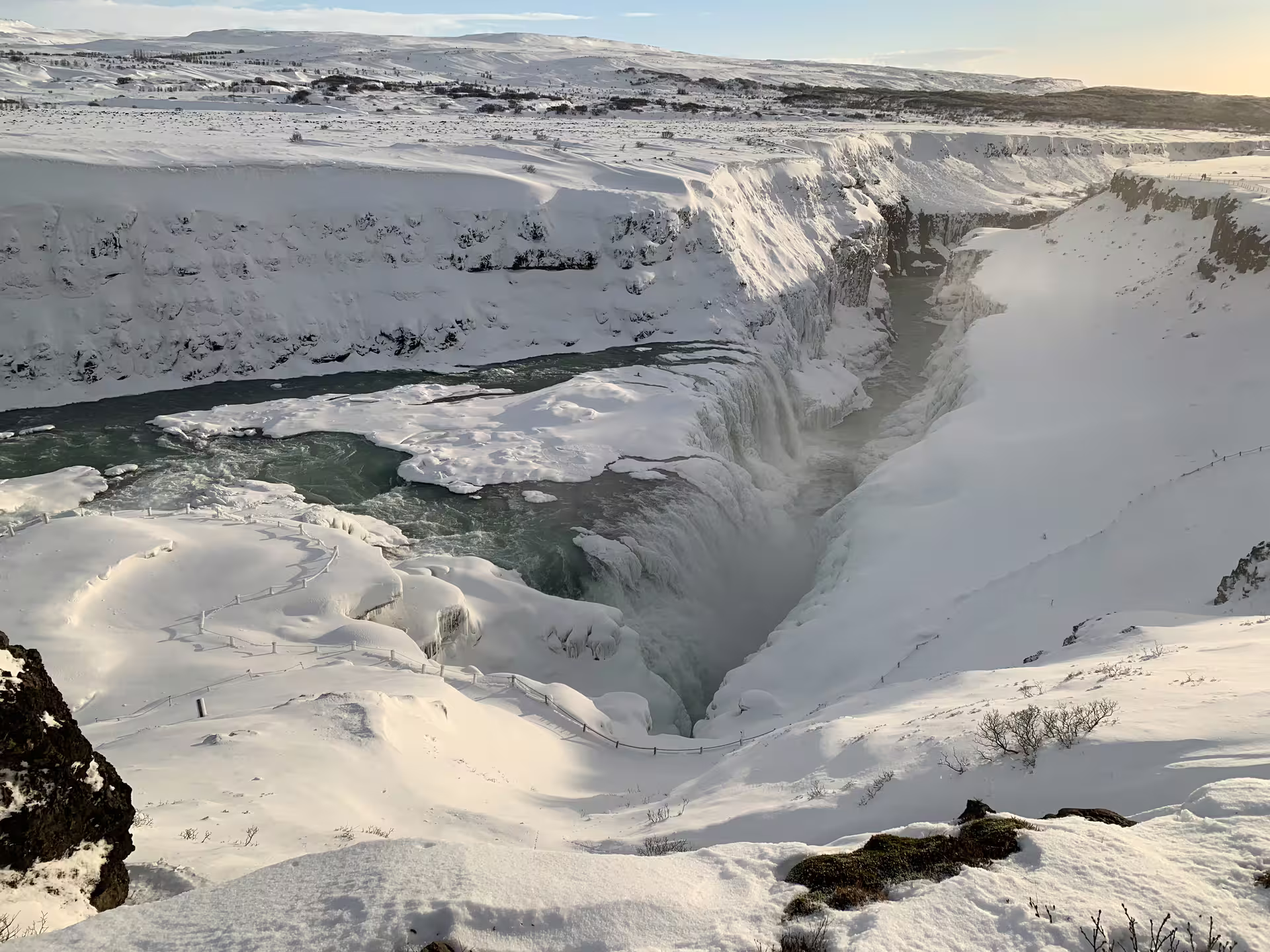 Gullfoss waterfall in Iceland covered in snow and ice with turquoise river flowing through canyon in winter