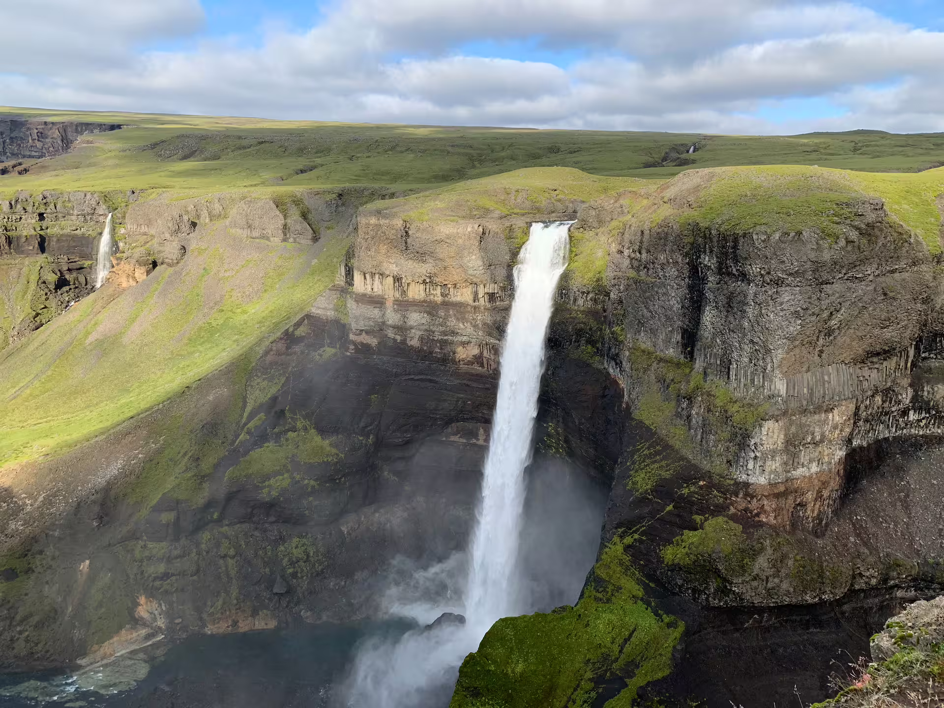 Háifoss waterfall plunging into canyon with green highlands in Iceland on a sunny day