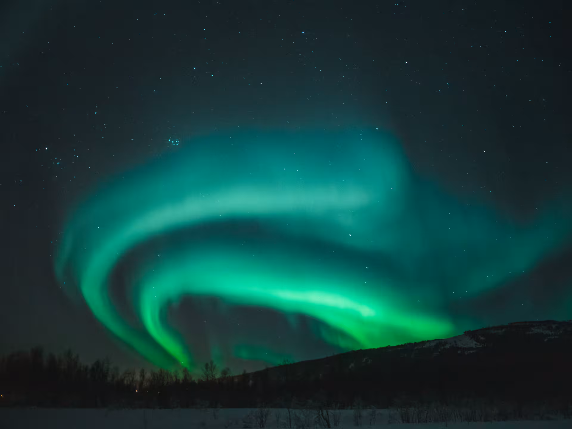 Vibrant green aurora borealis swirling over snowy Iceland landscape at night