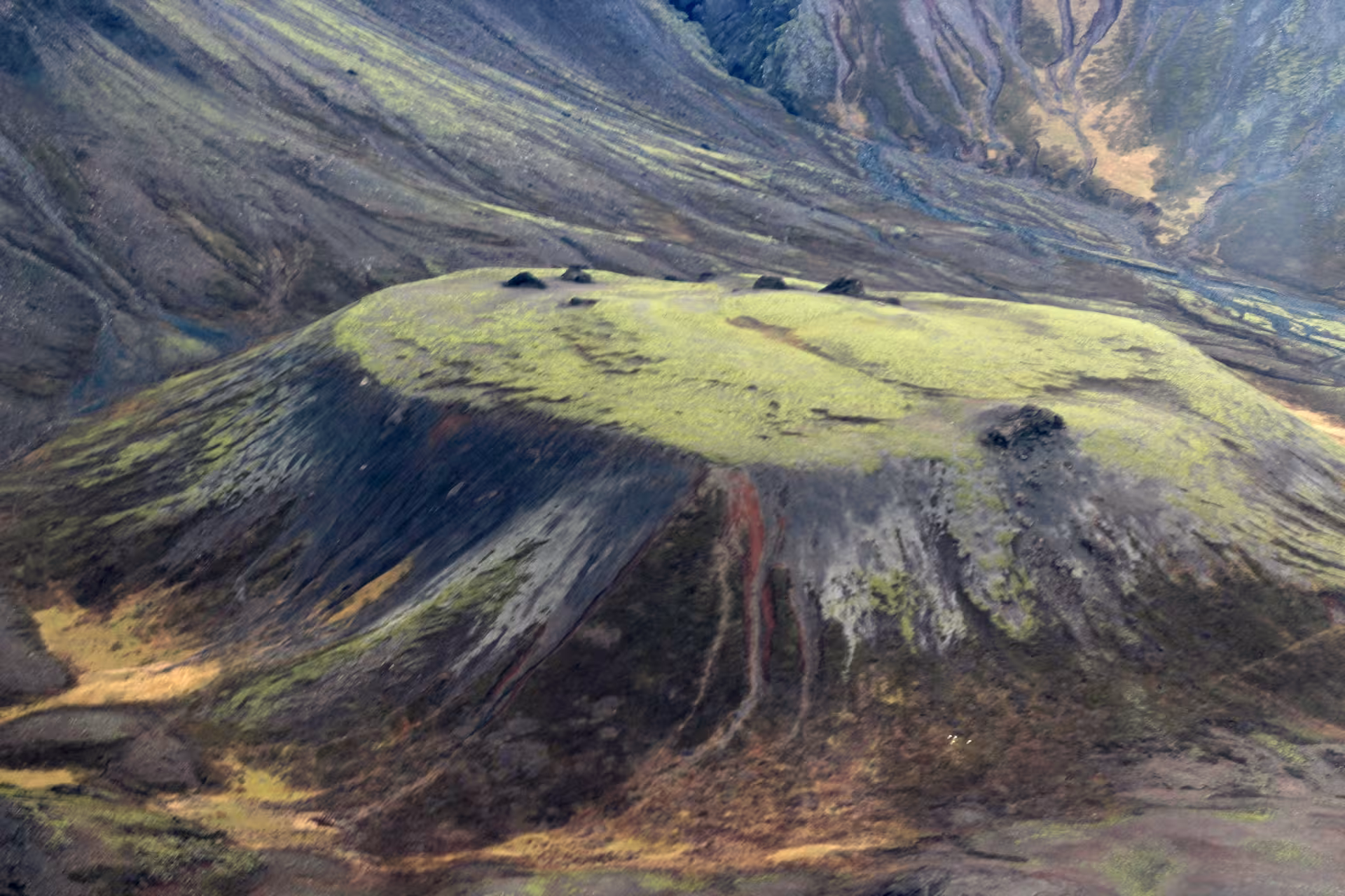 Aerial view of a green moss-covered volcanic crater cone in Iceland's volcanic landscape