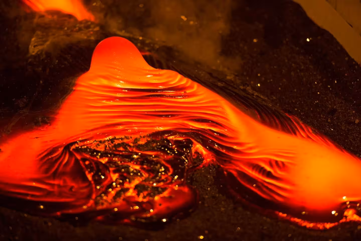 Bright red molten lava flowing during a live demonstration that recreates the intensity of a volcanic eruption in Iceland.