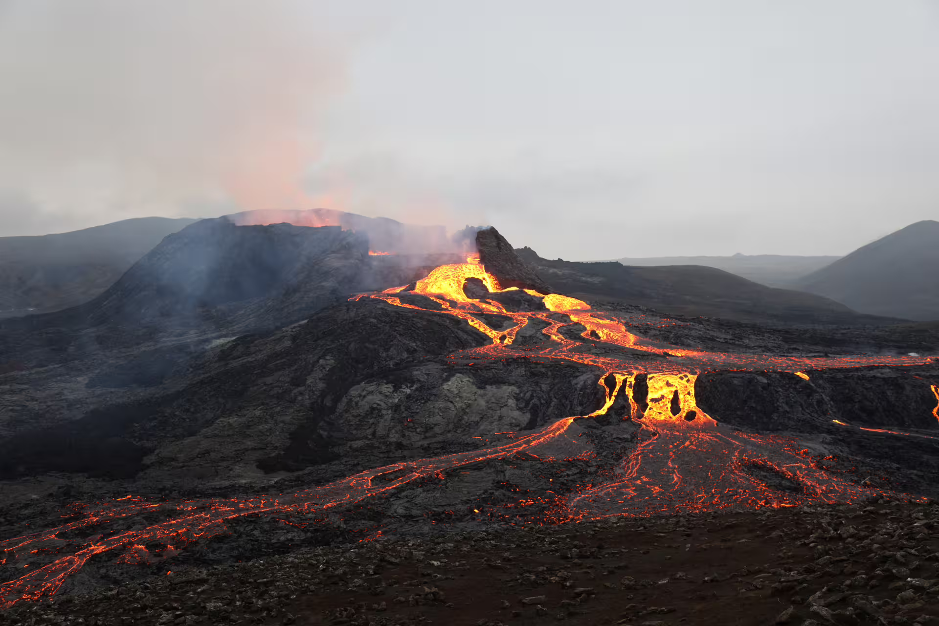 Glowing lava flows down a volcanic mountain during an active eruption in Iceland