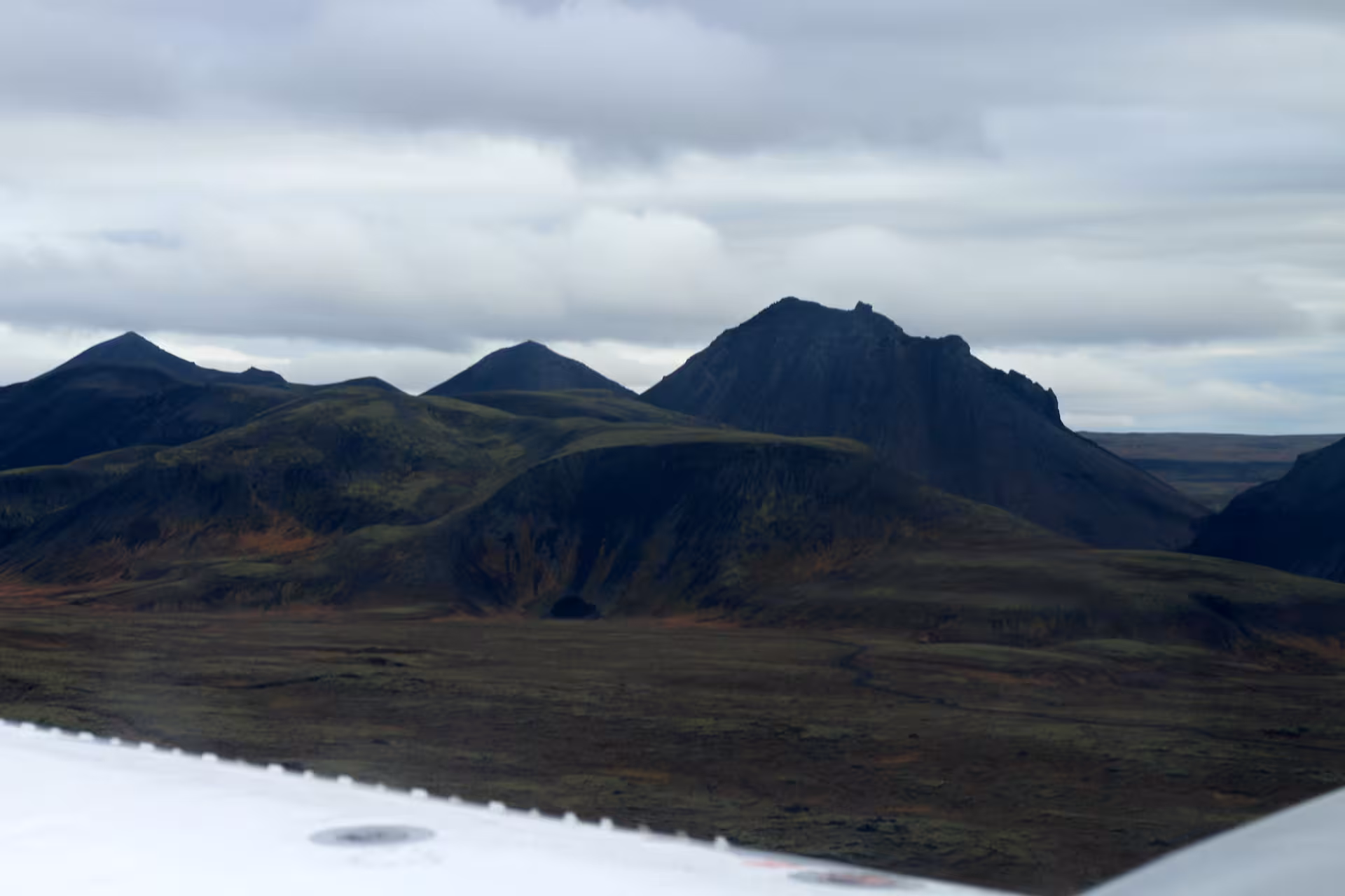 Aerial view of dark volcanic mountains and rugged lava fields in Iceland from airplane window