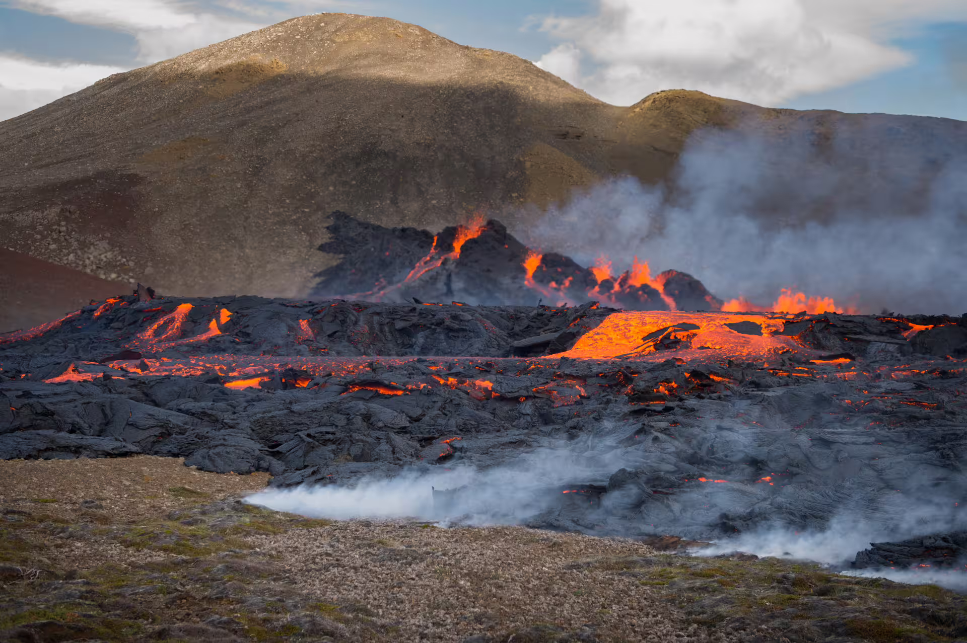 Active volcanic eruption with glowing orange lava flows and smoke near Reykjavik, Iceland