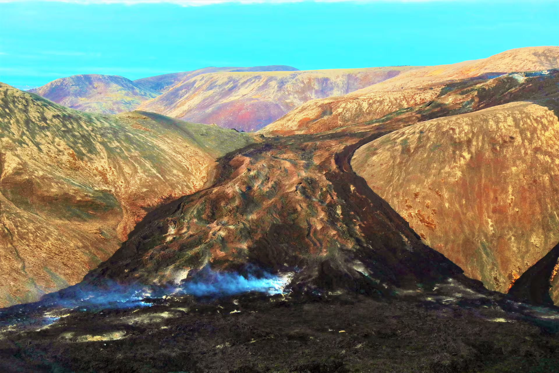 Steaming volcanic ridge with colorful mineral-stained mountains in Iceland's highland landscape