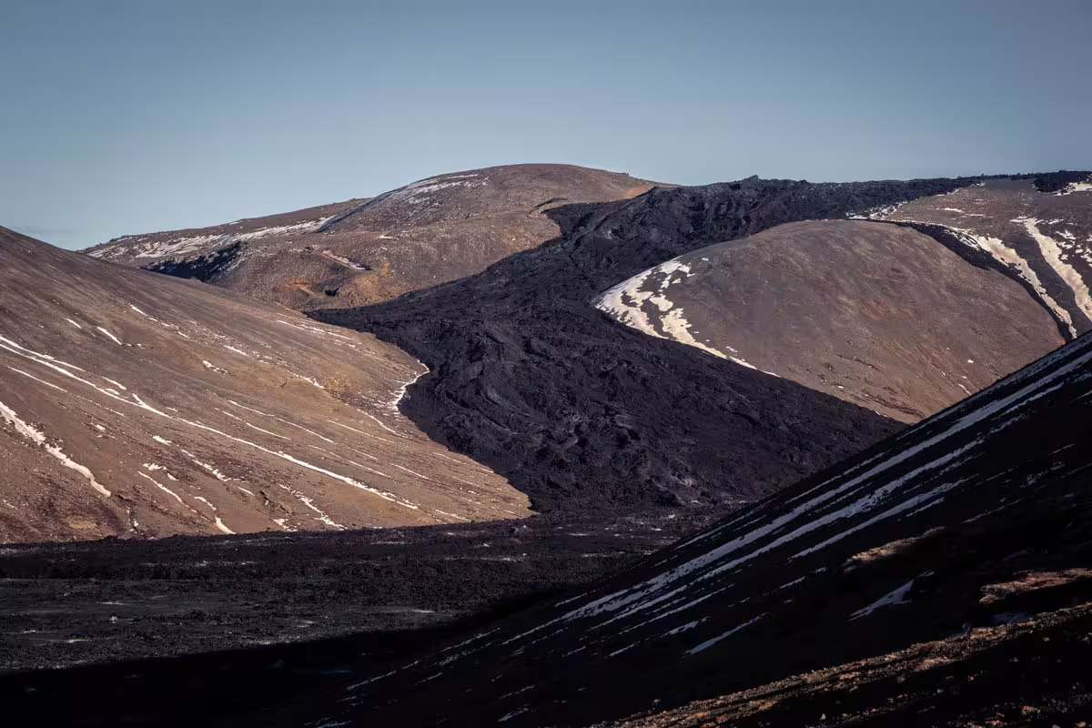 Dark volcanic lava fields and snow-dusted craters on an Icelandic volcano landscape