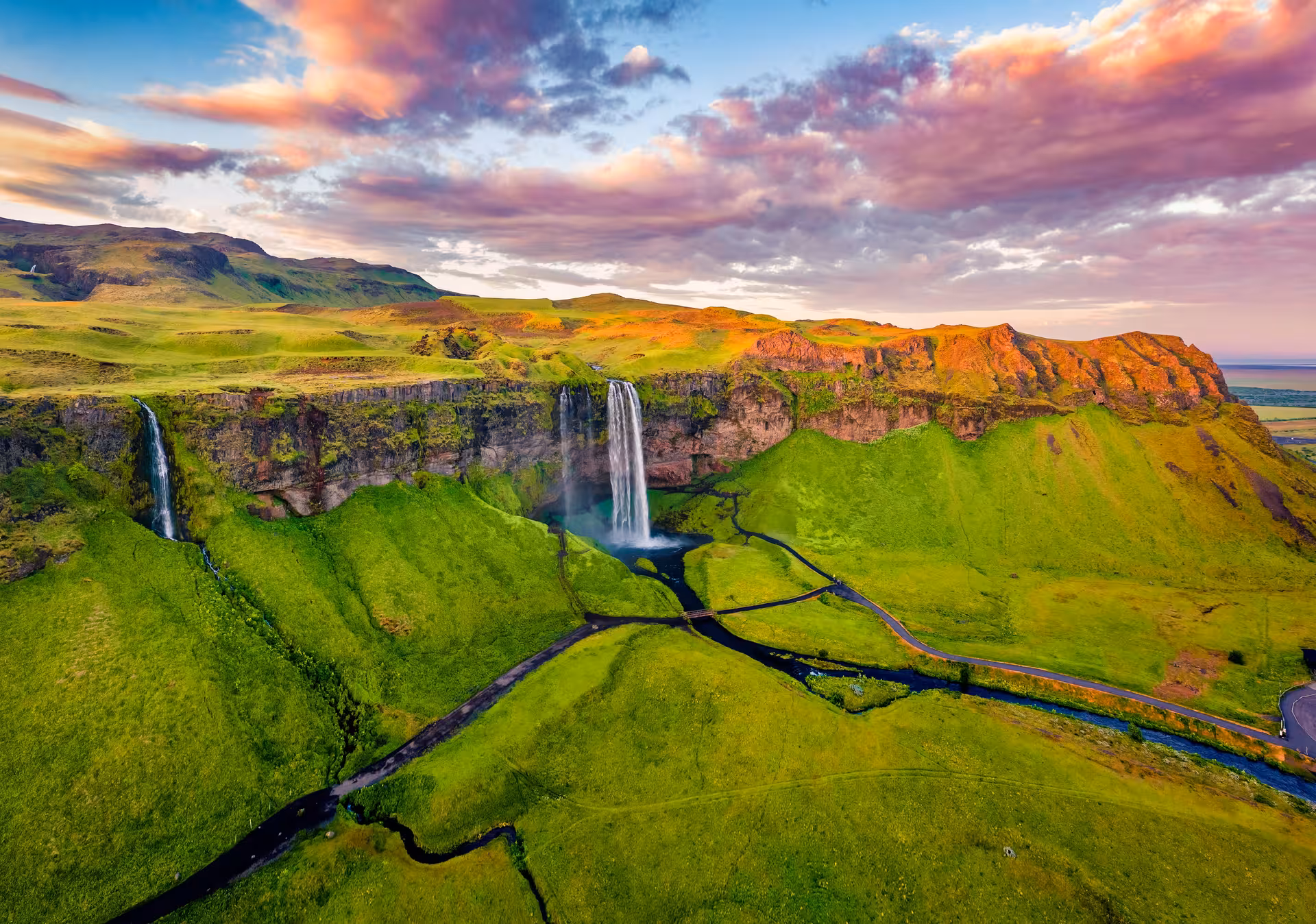 Aerial view of Seljalandsfoss waterfall cascading over green cliffs in Iceland at sunset