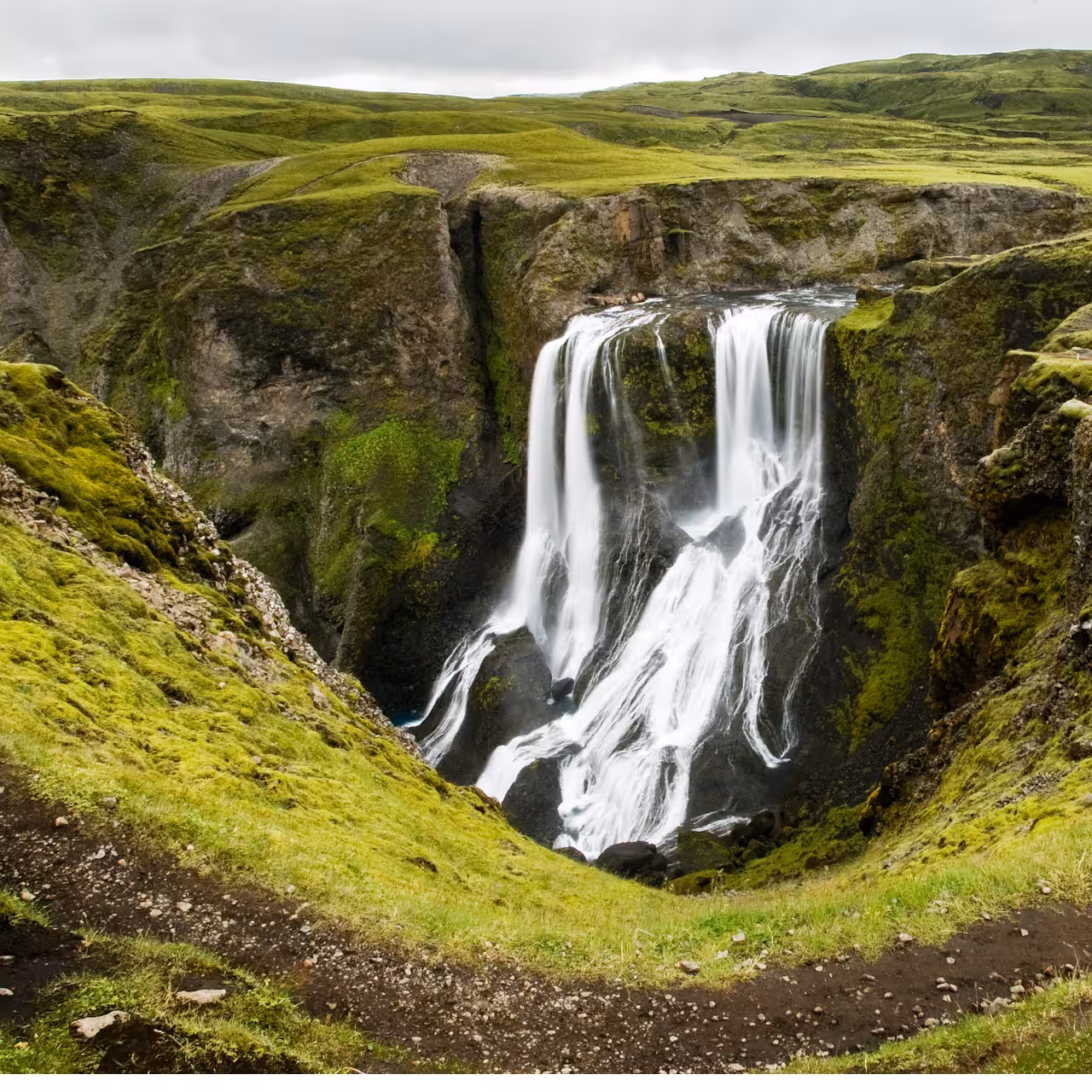 Stunning Iceland waterfall cascading into mossy green canyon on private Laki Craters Super Jeep tour from Vik