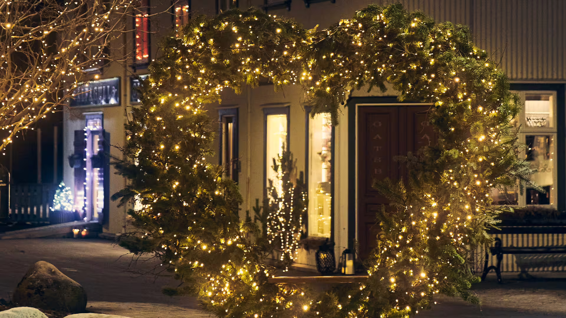 Heart-shaped evergreen arch adorned with warm fairy lights outside an Icelandic shop during Christmas advent season