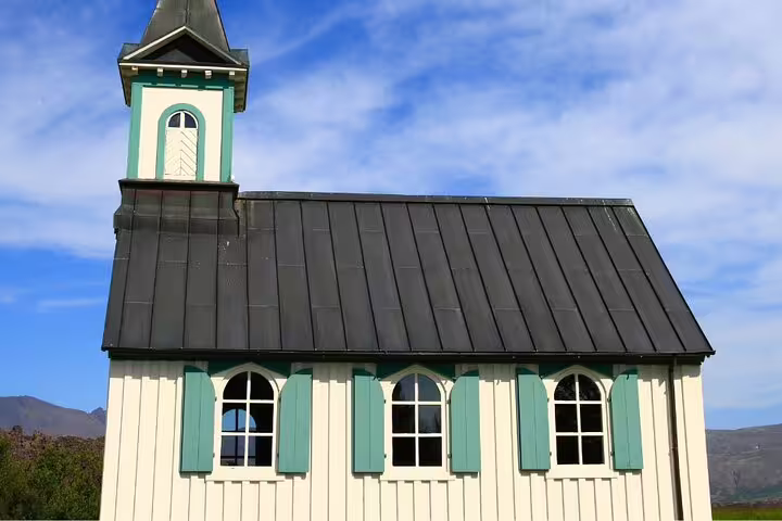 White Icelandic church with teal shutters and black metal roof near Golden Circle