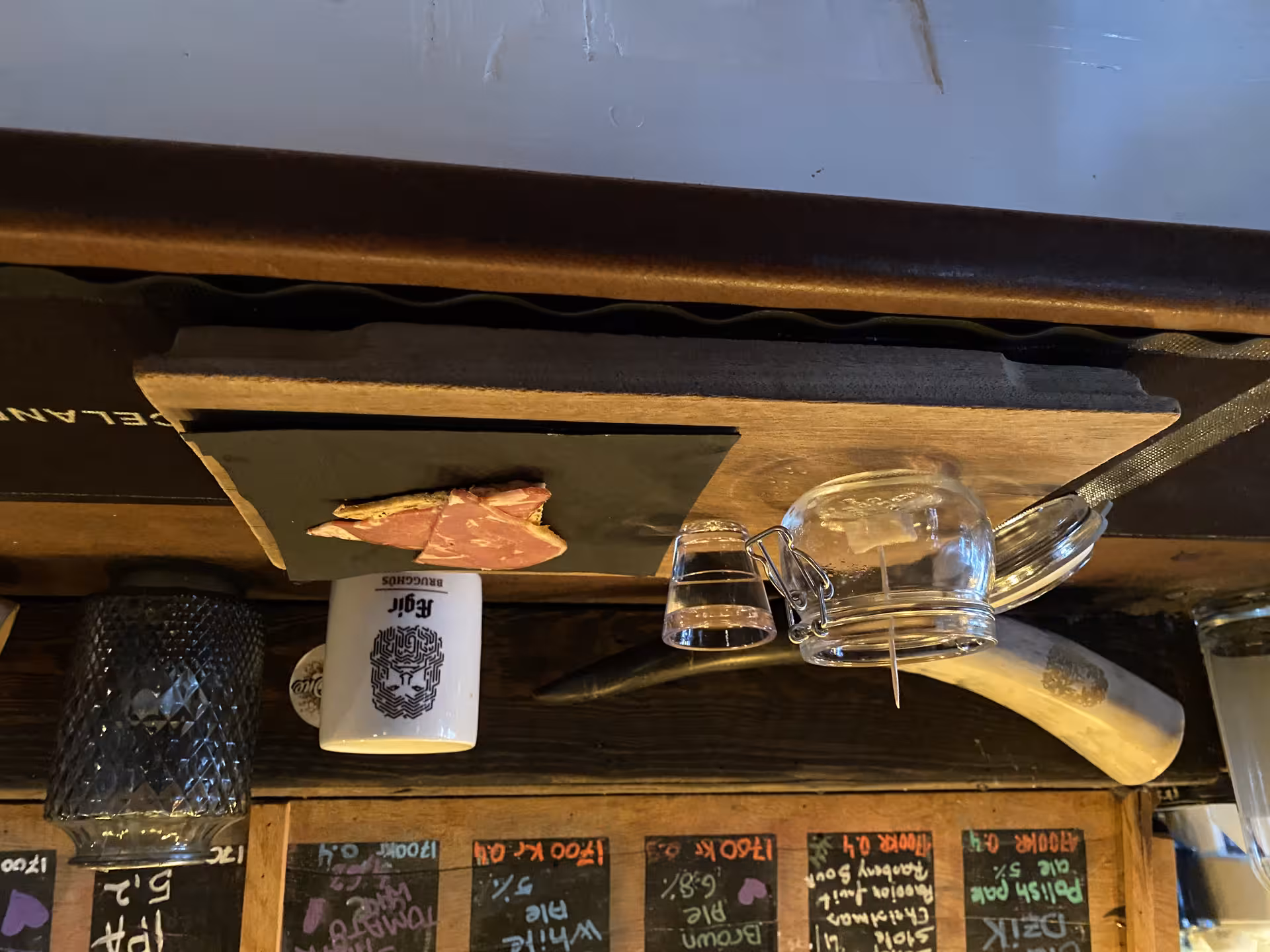 Icelandic craft beer menu chalkboard with traditional cured meat and glass jars on wooden bar shelf