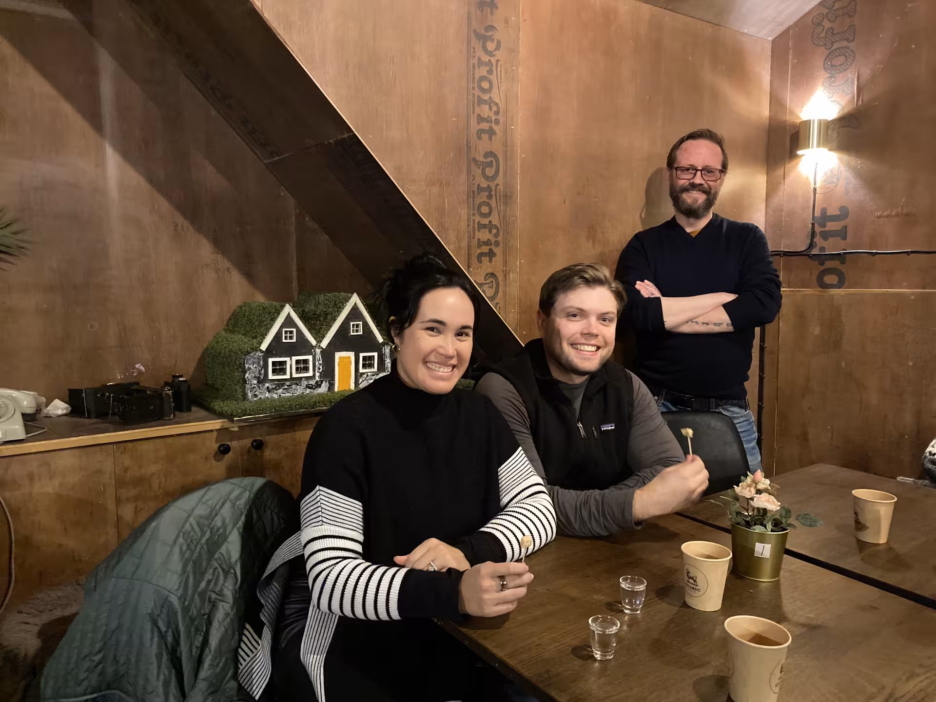 Three smiling guests at a cozy wooden table with drinks on an Icelandic food tour