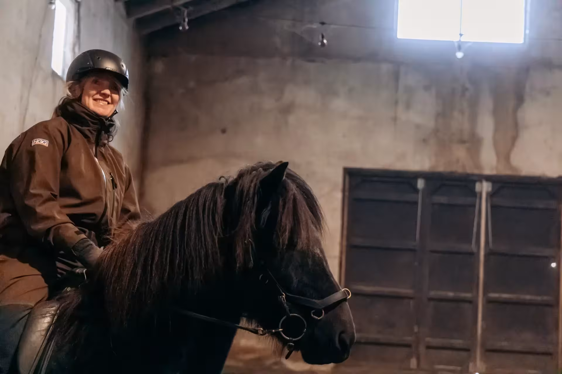 Smiling rider on Icelandic horse in indoor arena, private North Iceland horseback experience near Goðafoss