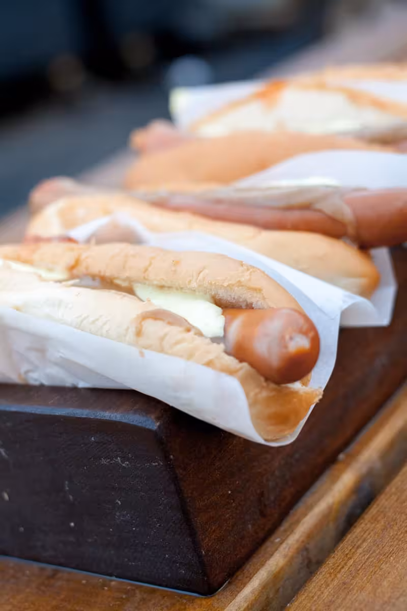 Fresh Icelandic hot dogs wrapped in paper served on a wooden tray during a city walk food tasting experience