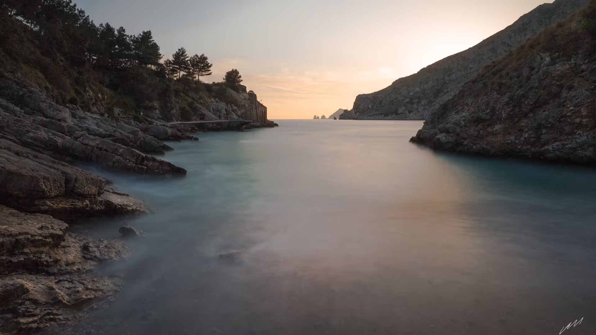 Sunset over Ieranto Bay with calm turquoise water, rocky cliffs and Punta Campanella trekking coast, Amalfi area