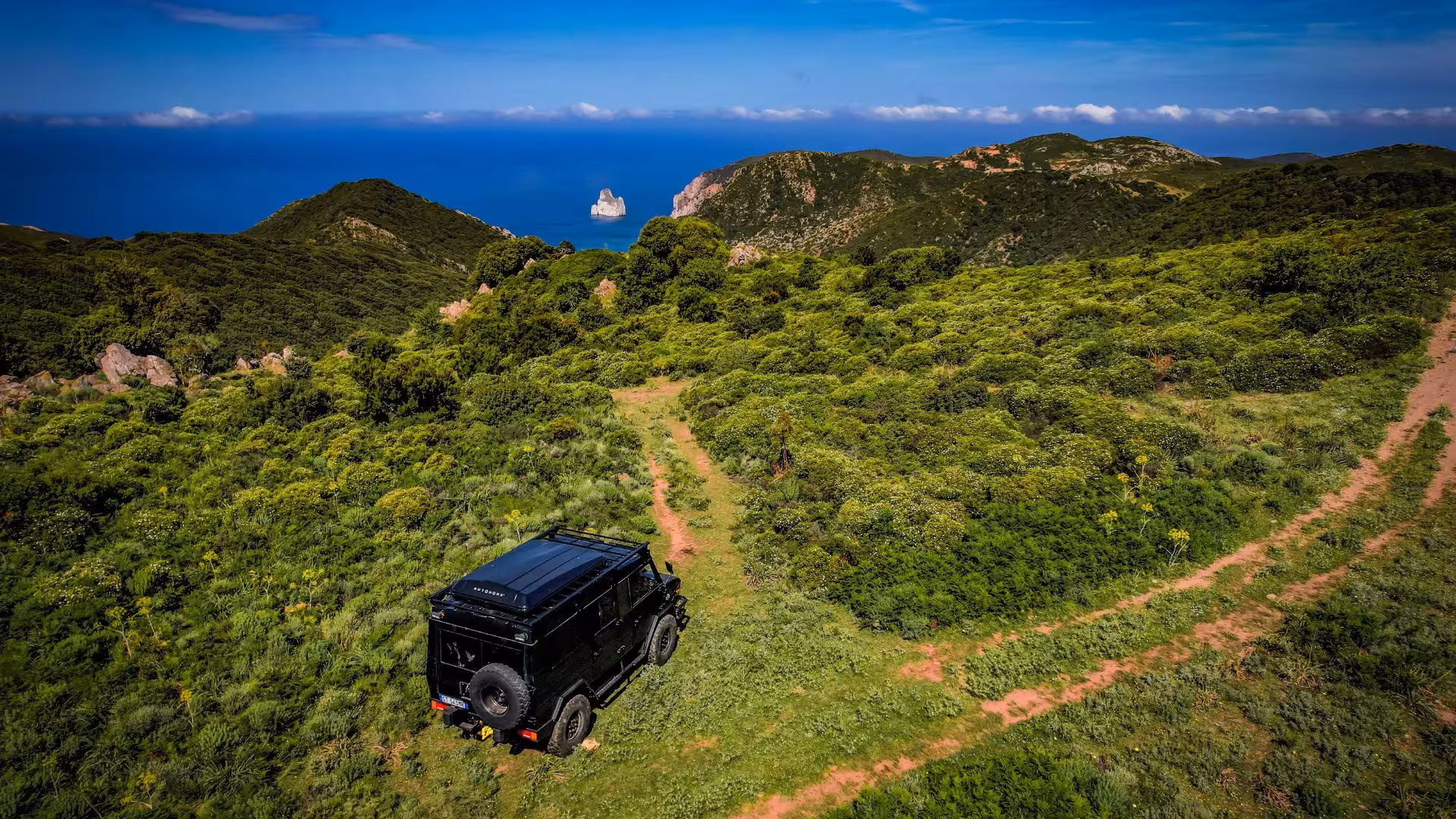 Scenic jeep tour path in Iglesias with lush greenery and sea views, ideal for adventure seekers.